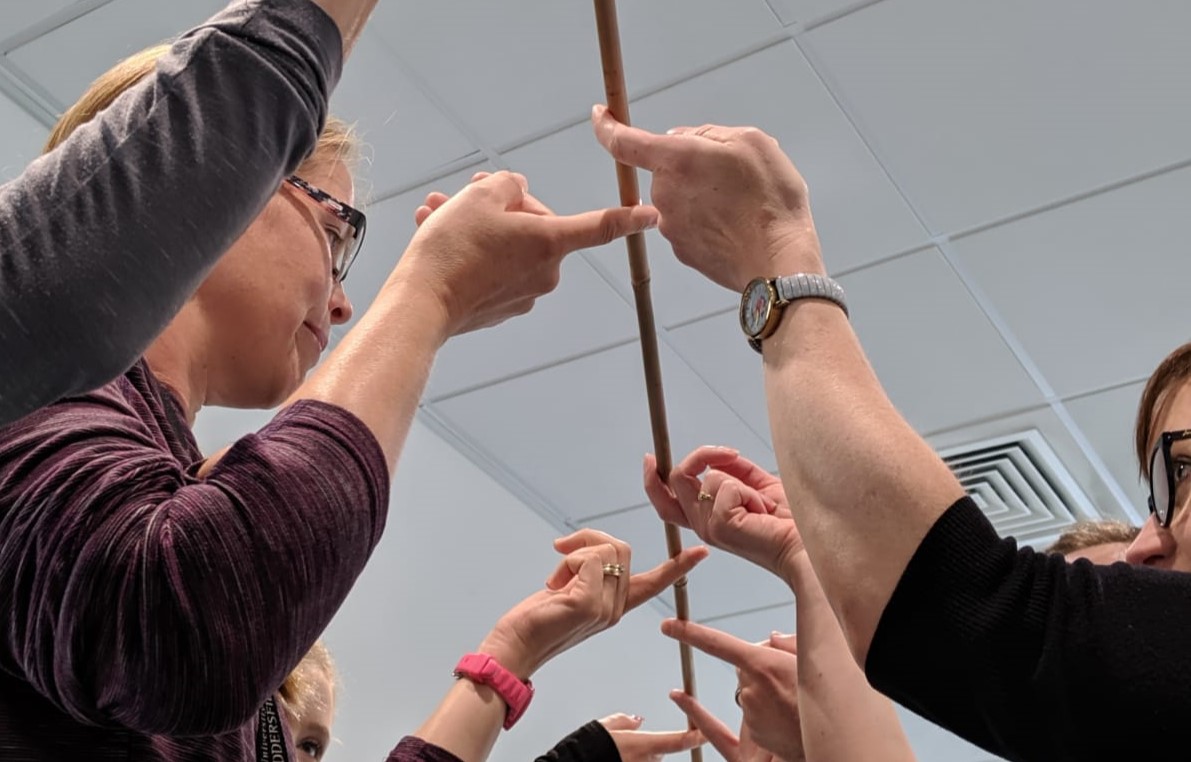 Students holding a cane with their finger tips.